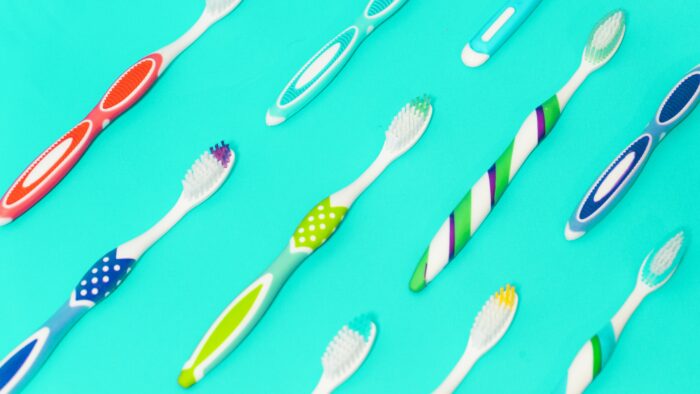 Colourful used toothbrushes on a turquoise background